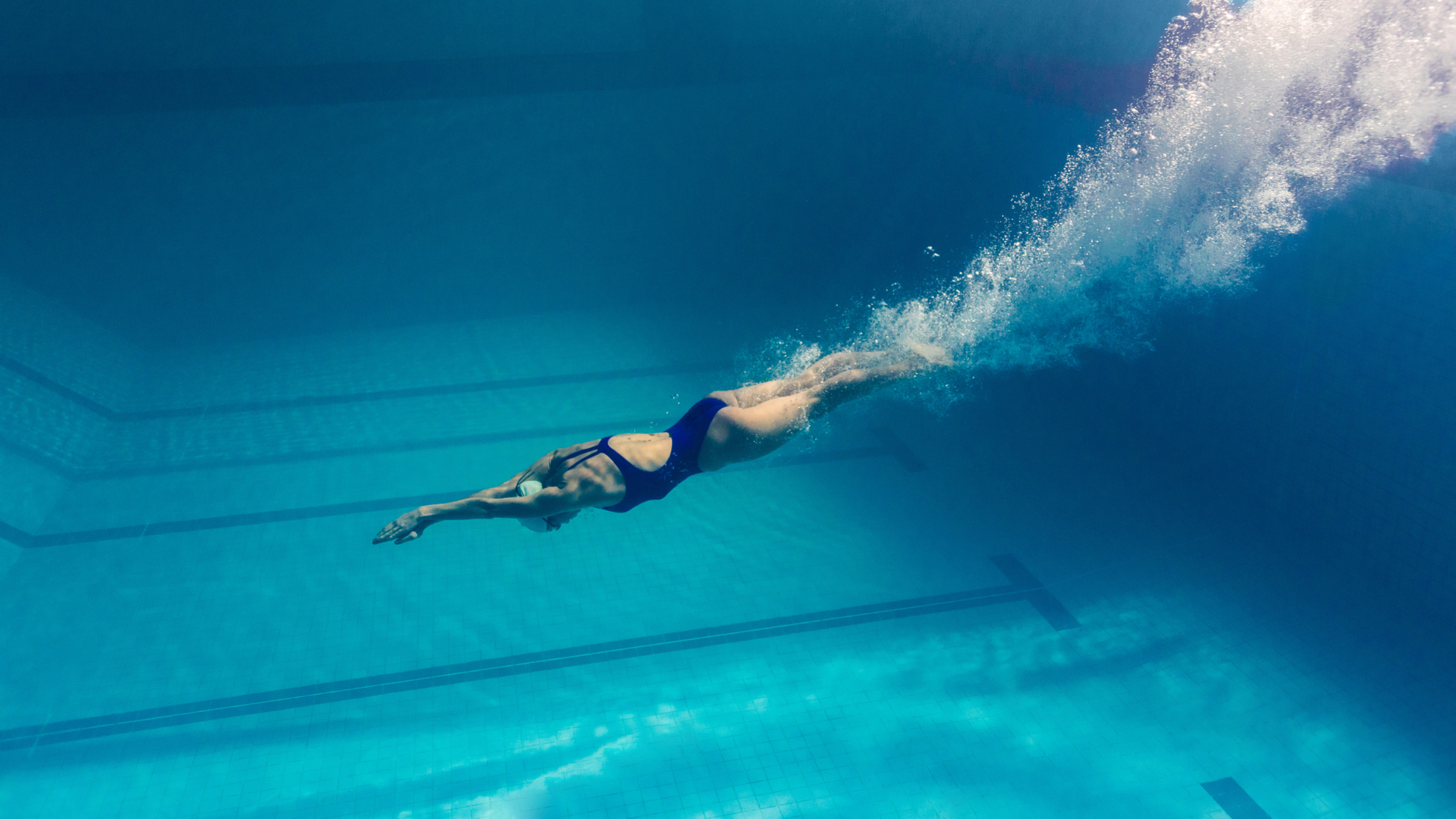 Underwater snapshot of woman alone after diving into the deep end of a pool. Symbolizes being a solo-founder in business.